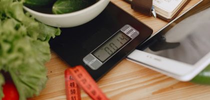 A bowl of fresh vegetables on a kitchen scale with measurement tools, depicting a healthy lifestyle.