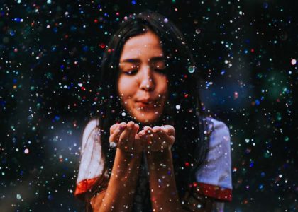 Joyful teenage girl blows vibrant particles, creating a magical atmosphere